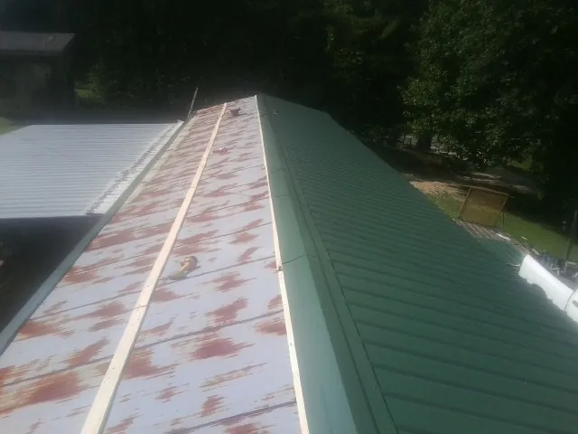 Old rusted panels beside newly installed green metal roofing — Wind Damage Roof Repair by Roofing Brothers in Lady Lake