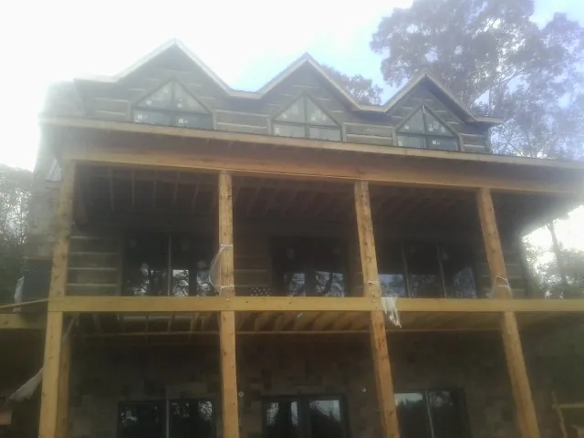 Dormers and porch framing on a large log home under construction — Roof Coating work by our crew in Lady Lake