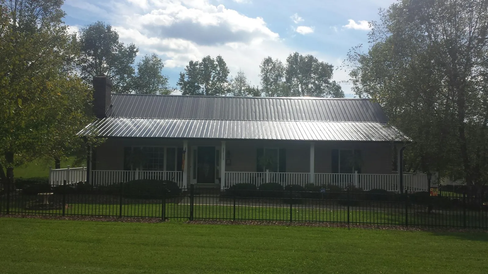 Gray metal roof on a brick ranch with a full width front porch — Gutter Guard Installation work by our crew in Lady Lake