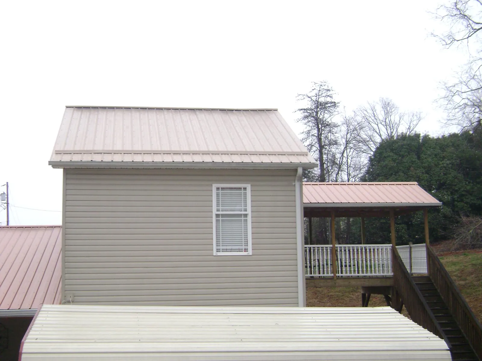 Tan metal roofs on a two story addition and attached porch, from a Roof Replacement job in Lady Lake