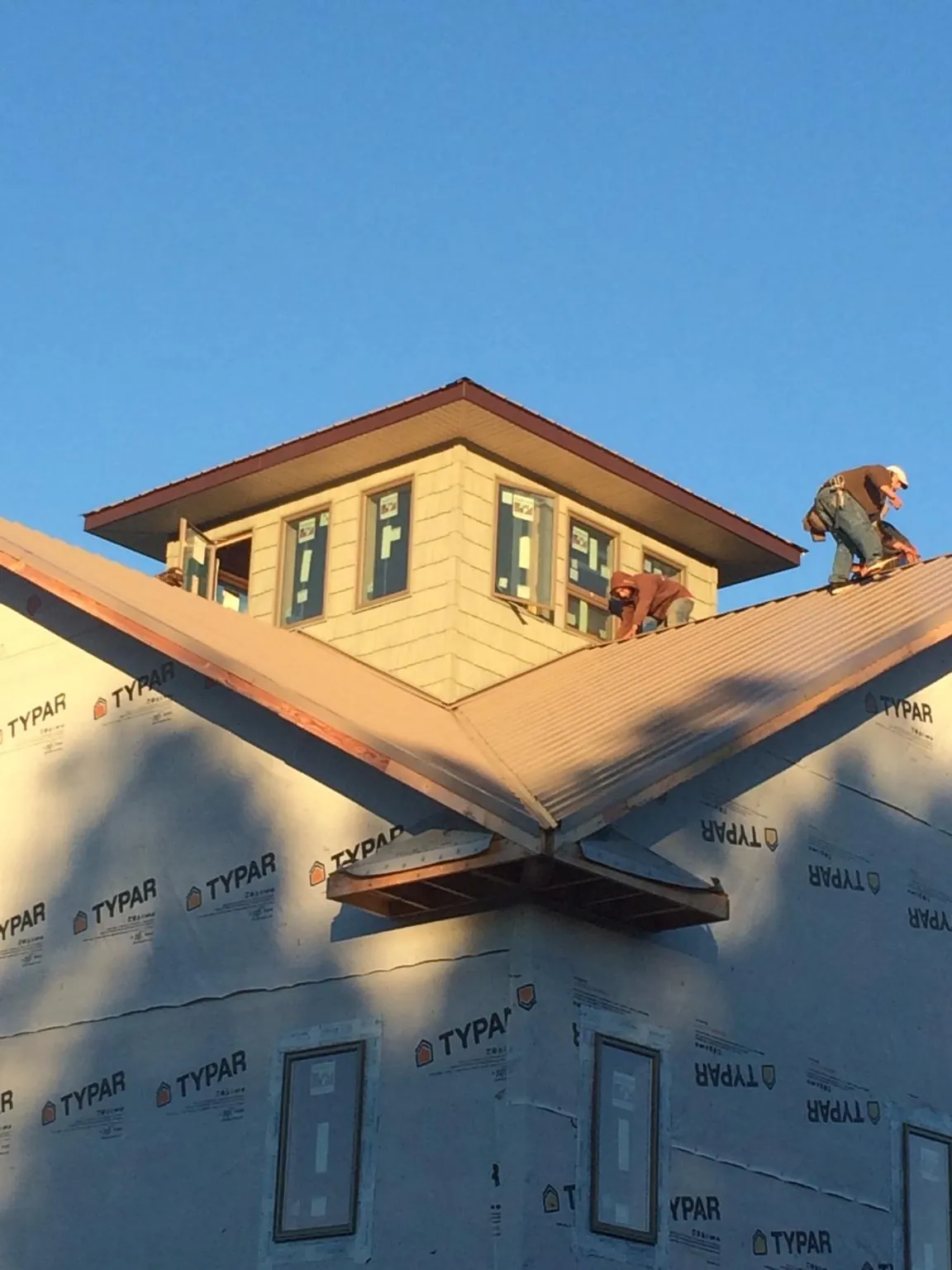 Roofers working around a rooftop cupola on a new metal roof at sunset — Roof Waterproofing in Lady Lake by Roofing Brothers